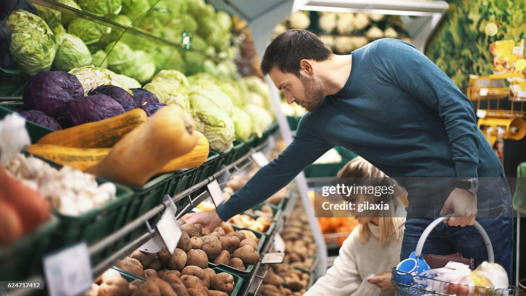 Couple in supermarket buying vegetables.
