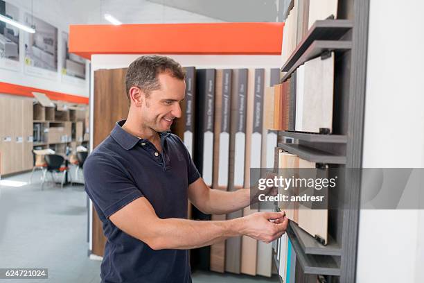 homme dans un magasin au sol regardant des échantillons de bois - show room photos et images de collection