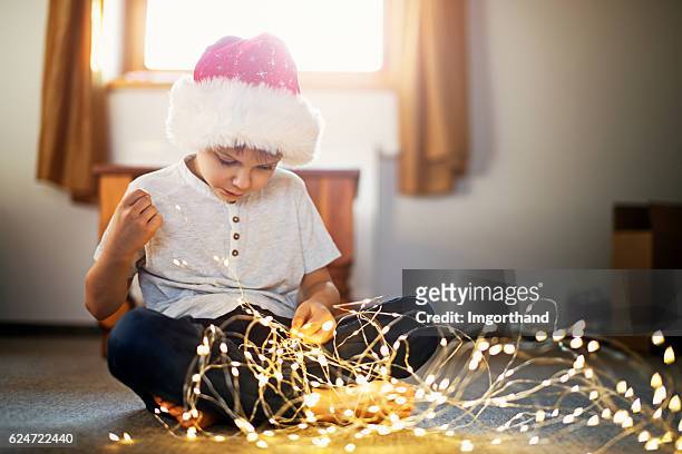 little boy playing with christmas lights on christmas morning - tangled christmas lights stock pictures, royalty-free photos & images