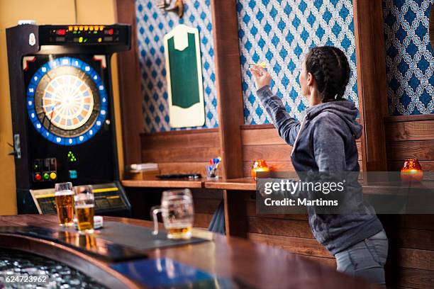 girl playing darts at bar - bar girl stockfoto's en -beelden