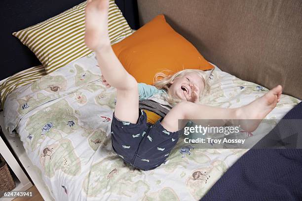 young boy laughing on his bed. - tempe arizona stock pictures, royalty-free photos & images