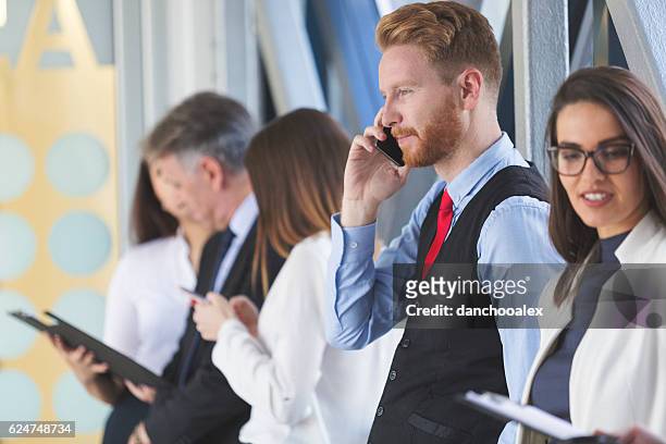 young man speaking on the smart phone in the lobby - cinco pessoas imagens e fotografias de stock