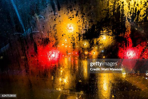 rain on a car windscreen and city lights reflecting on a wet street - car red light stock pictures, royalty-free photos & images