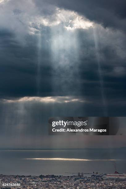 rays of sunlight breaking through dramatic clouds over sea - alexandros maragos stock pictures, royalty-free photos & images