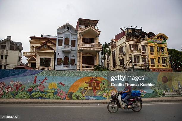 Hanoi, Vietnam Multi-family houses on a street in Hanoi. In the foreground stands an colorful painted wall on October 30, 2016 in Hanoi, Vietnam.