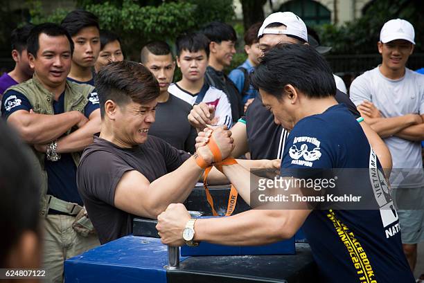 Hanoi, Vietnam Two men doing arm wrestling surrounded by spectators on a street in Hanoi on October 30, 2016 in Hanoi, Vietnam.