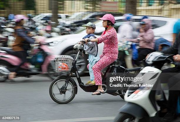 Hanoi, Vietnam A mother is driving with her son on a moped in the street traffic of Hanoi. The child does not wear a protective helmet on October 30,...