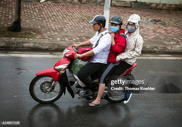 Hanoi, Vietnam Three Vietnamese people with respiratory masks driving on a motorbike through the city traffic in Hanoi on October 30, 2016 in Hanoi,...