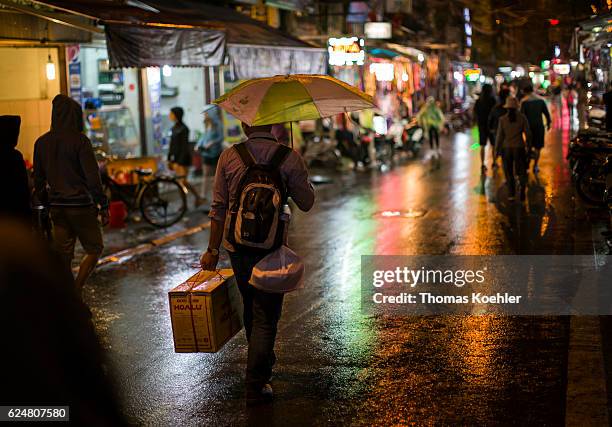 Hanoi, Vietnam A man runs with his shopping and a broken umbrella through a shopping street in Hanoi in the evening on October 30, 2016 in Hanoi,...