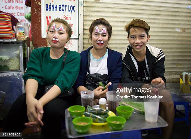 Hanoi, Vietnam Vietnamese teenagers sit at a street diner. The young women are made up as cats on October 30, 2016 in Hanoi, Vietnam.