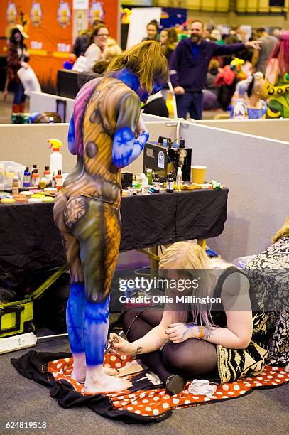 Body paint artists working on models throughout day 2 of the November Birmingham MCM Comic Con at the National Exhibition Centre in Birmingham, UK on...