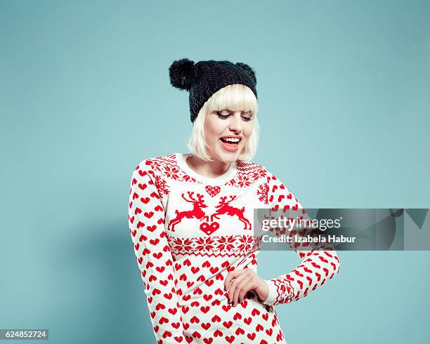 happy blonde young woman wearing xmas sweater and bobble hat - bobble hat stock pictures, royalty-free photos & images