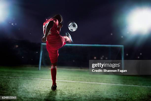 soccer player kicking ball towards goal - gol fotografías e imágenes de stock