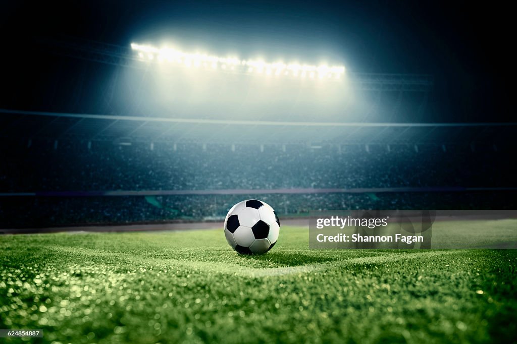 Soccer ball in sports field in stadium at night