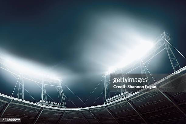 bright stadium lights against a dark blue sky - stadium lights stock-fotos und bilder