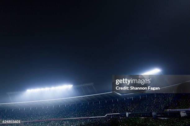 bright stadium lights with crowd at night - lumière de stade ou de chantier photos et images de collection