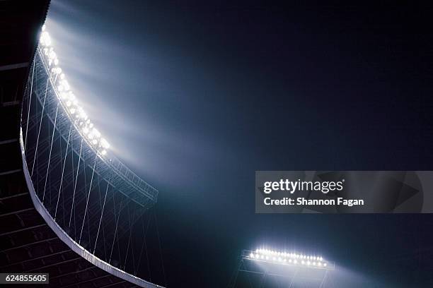 stadium lights glowing against night sky - stadio foto e immagini stock