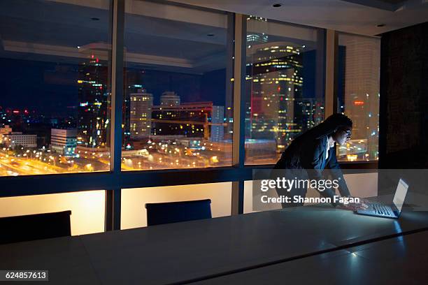 woman views laptop on table at night - african cityscape stock pictures, royalty-free photos & images