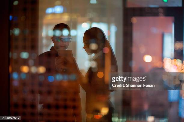 coworkers looking at tablet in office - light reflection stock-fotos und bilder