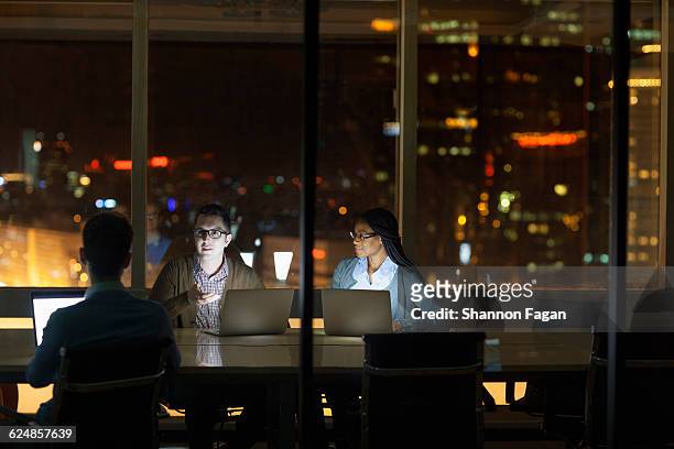 colleagues collaborating in office at night - public building stock photos et images de collection