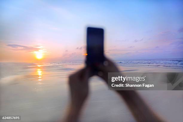 Person taking a photo at sunrise on the beach