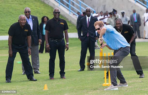 Prince Harry plays cricket as Sir Andy Roberts, Sir Vivian Richards and Sir Curtly Ambrose look on during a Youth Sports Festival at the Sir Vivian...