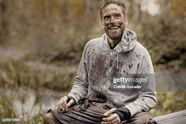 caucasian blonde handsome man sitting smiling during a mud run - mud stock pictures, royalty-free photos & images