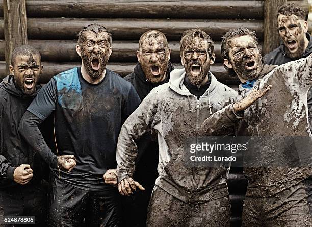 multiethnische schlammlauf team von männern schreien während hindernis-kurs - herausforderung stock-fotos und bilder