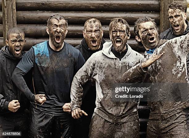 squadra multietnica di uomini che urlano durante il percorso ad ostacoli - mud foto e immagini stock