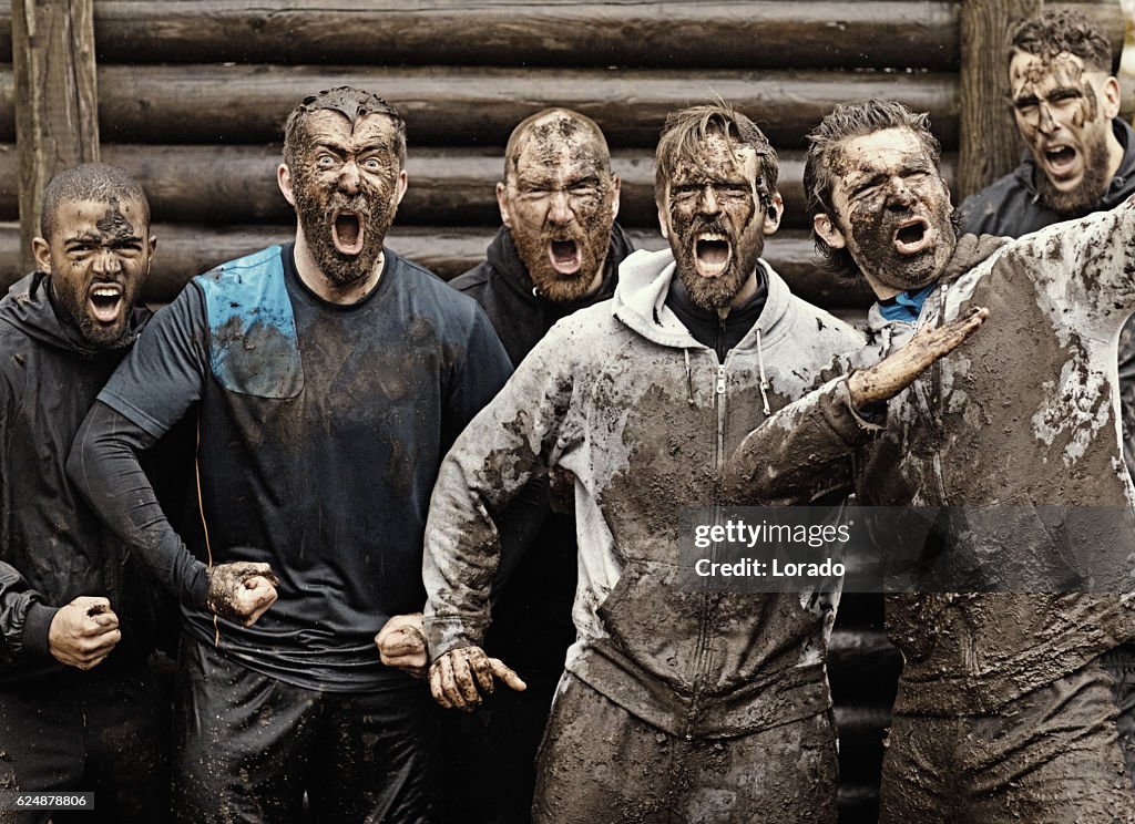 Multiethnic mud run team of men yelling during obstacle course
