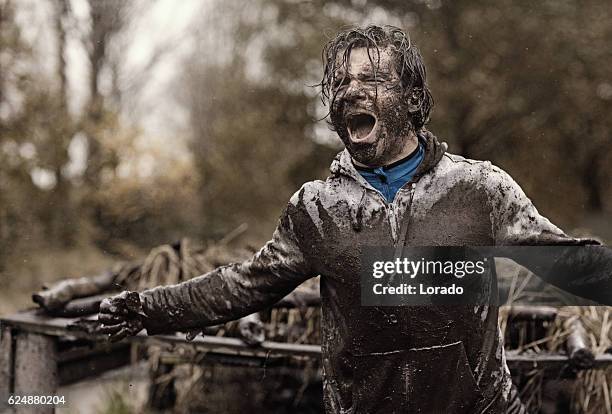 kaukasische brünette stattlichen mann an hindernis während einer schlammbahn - mud run stock-fotos und bilder