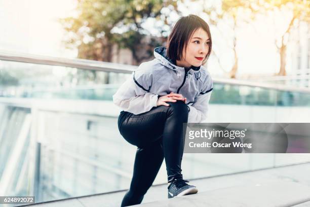 Female runner stretching legs on bench on street