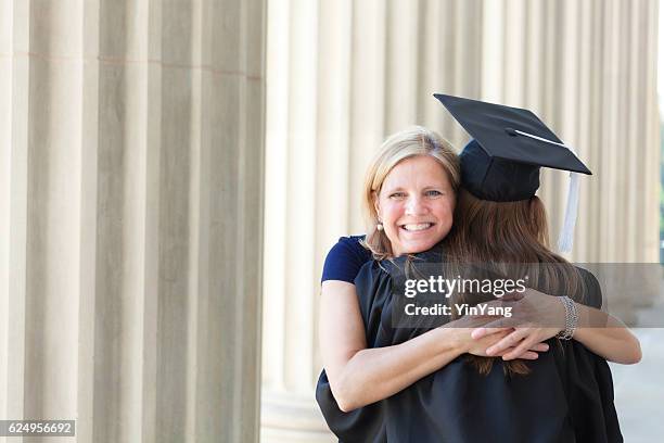 glückliche mutter umarmen und tochter gratulieren in university graduation-zeremonie - sekundarschule stock-fotos und bilder