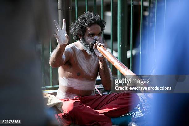 busker sitting and blowing didgeridoo - aboriginal artwork stockfoto's en -beelden