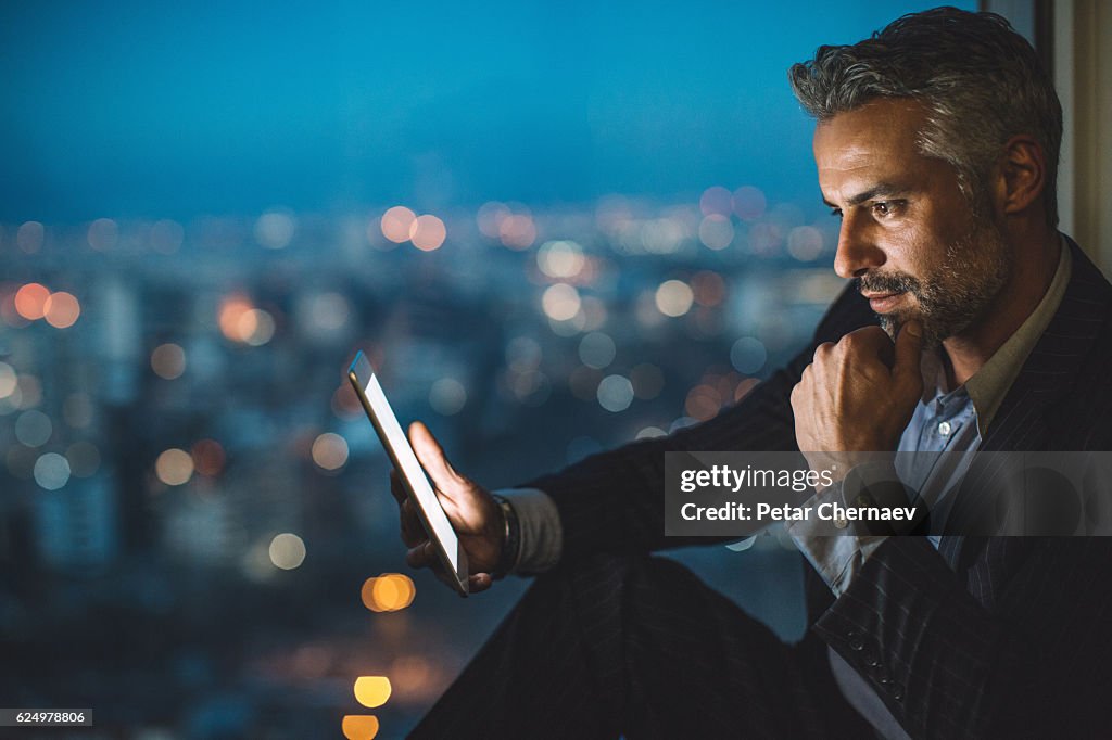 Businessman looking at digital tablet at night