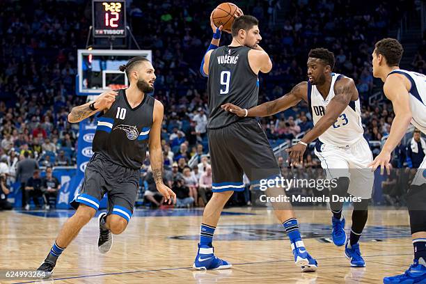 Wesley Matthews of the Dallas Mavericks guards Nikola Vucevic and Evan Fournier of the Orlando Magic at Amway Center on November 19, 2016 in Orlando,...