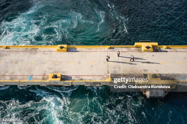 local crew waving goodbye to the departing cruise ship from the pier, as the water swirls around them. - cruise crew stock pictures, royalty-free photos & images