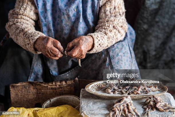 close-up of old woman's hands peeling frog legs for sale in the market in cusco. - woman frog hand stockfoto's en -beelden