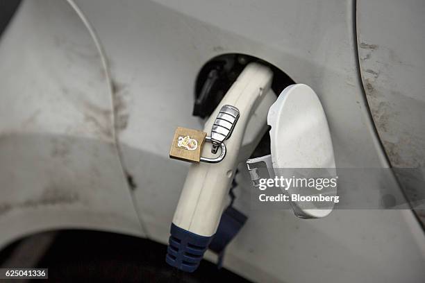 Personal miniature padlock sits on a charging plug whilst it refuels a Mitsubishi Motors Corp. I-MiEV electric vehicle at Kongens gate near Akershus...