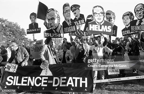 Members of AIDS activist group ACT UP hold up signs of George W. Bush, Ronald Reagan, Nancy Reagan, Jesse Helms and other with the word "Guilty"...