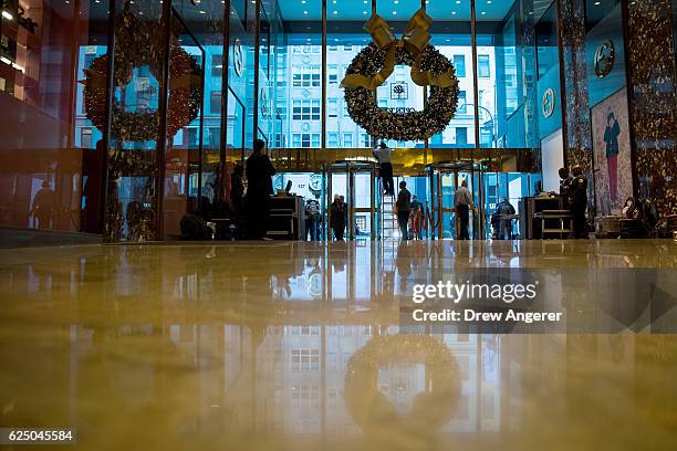 Maintenance worker makes adjustments on a wreath hanging at the entrance of Trump Tower, November 22, 2016 in New York City. President-elect Donald...