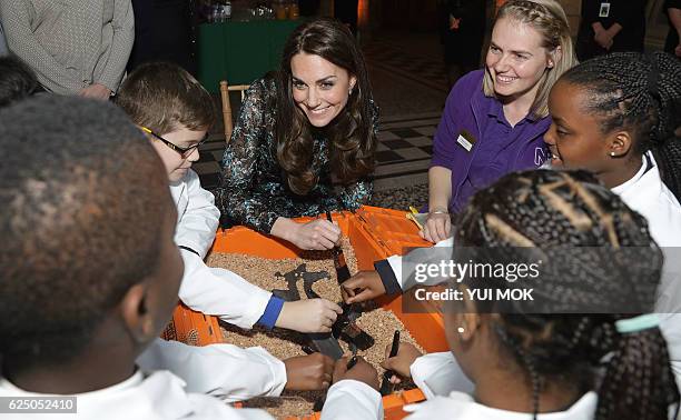 Britain's Catherine, Duchess of Cambridge , examines a replica diplodocus fossil at the Natural History Museum in London on November 22 as she...