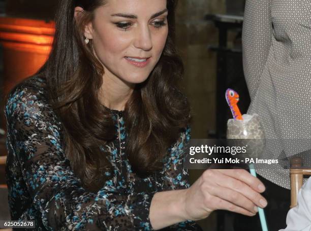 The Duchess of Cambridge makes a dinosaur egg whilst attending a children's tea party with pupils from Oakington Manor Primary School in Wembley, at...