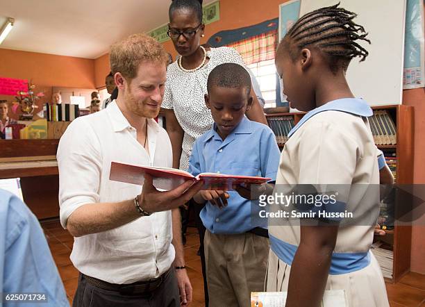 Prince Harry reads a book to children as he visits Holy Trinity Primary School on the third day of an official visit on November 22, 2016 in Barbuda,...