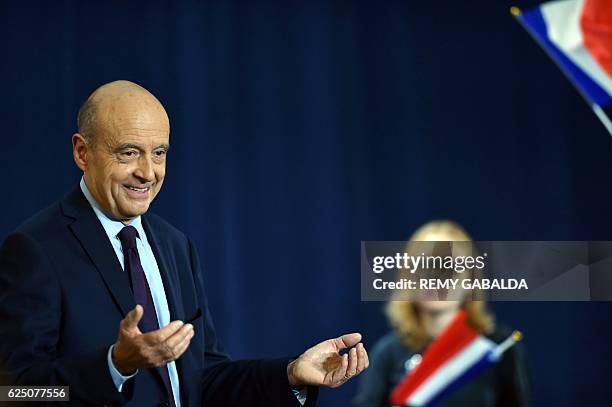 Supporters wave French flags as Alain Juppe, mayor of Bordeaux and candidate for the French right-wing presidential primary, gestures during a public...