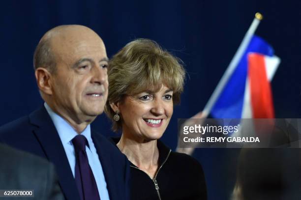 Supporter waves a French flag as Alain Juppe , mayor of Bordeaux and candidate for the French right-wing presidential primary, stands with his wife...