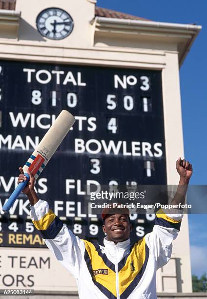 Brian Lara of Warwickshire celebrates his innings of 501 not out in front of the scoreboard at the end of the County Championship match between...