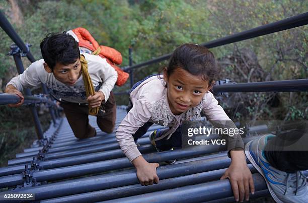 Children climb the steel ladder on the cliff on November 19, 2016 in Liangshan Yi Autonomous Prefecture, Sichuan Province of China. A new steel...