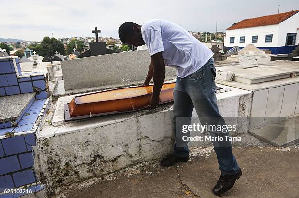 Father and pastor Leonardo Martins da Silva prepares to place the top section over the casket before the burial of his son Leonardo Martins da Silva...