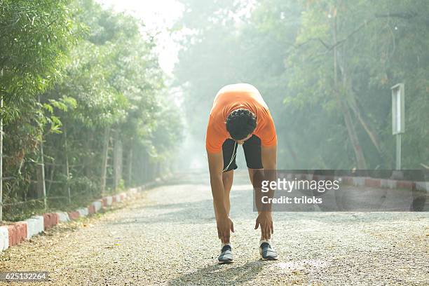 jogger warming up at park - touching toes stock pictures, royalty-free photos & images